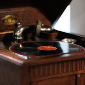 Zdjęcie przedstawia stary gramofon w drewnianej eleganckiej rzeźbionej obudowie.