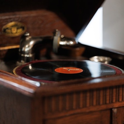 Zdjęcie przedstawia stary gramofon w drewnianej eleganckiej rzeźbionej obudowie.