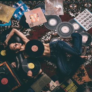 kobieta leży na dywanie wśród płyt winylowych